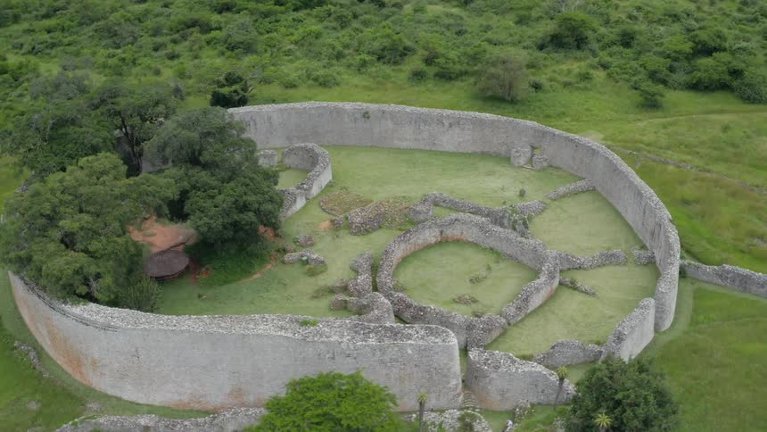 Circular stone ruins in the midle of a lush green field