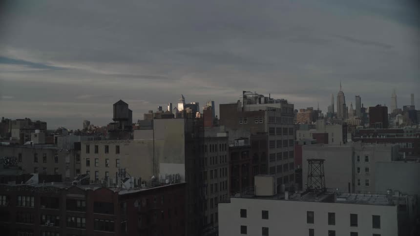 Clouds move over a large city when the sun is low in the sky