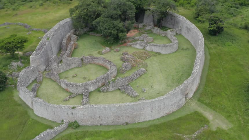 Aerial view of a massive round stone structure with trees inside known as the great enclosure in zimbabwe
