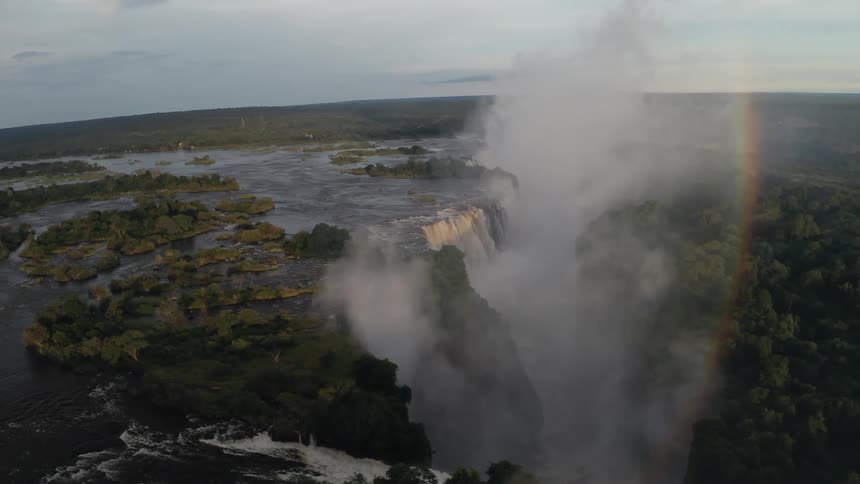 Aerial of mist and rainbow over waterfall