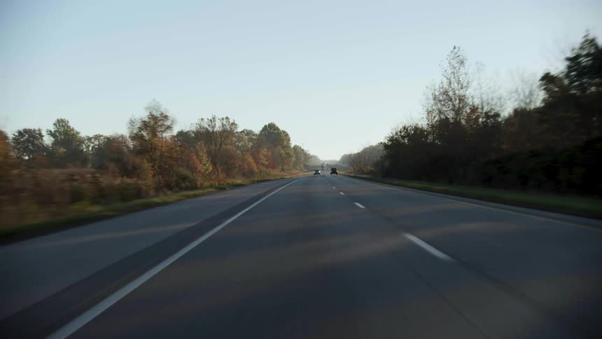 Vehicles travel along a road through the countryside during the day
