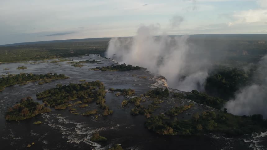 Water falls down cliff creating thick fog in forest stretching to the horizon
