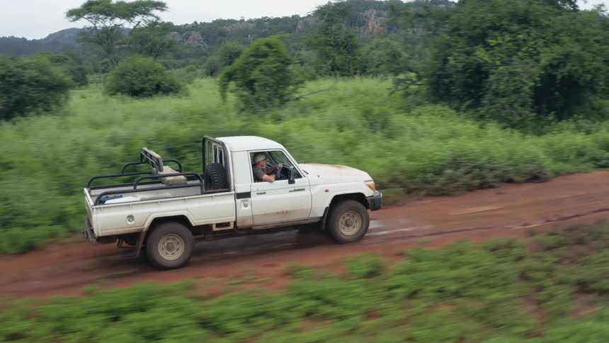 People are driving in a pick up truck through a rural area