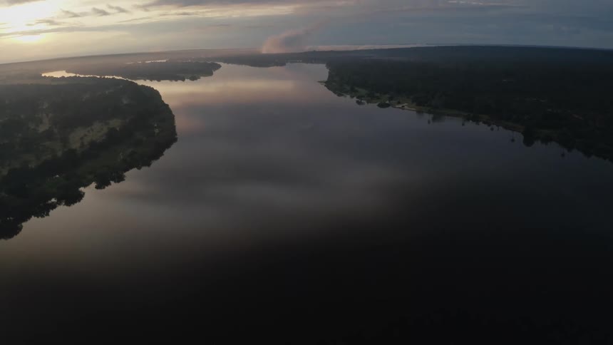 A wide smooth surfaced river reflecting sky and clouds