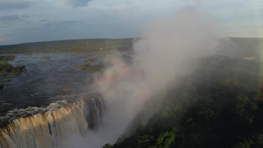Rainbow and mist over Victoria Falls at golden hour