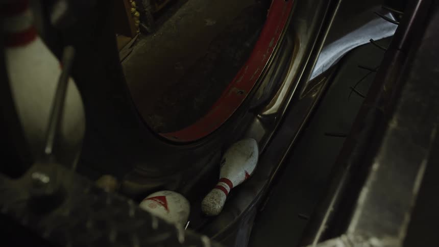 Dirty used bowling pins are moving on a conveyor belt in a bowling alley