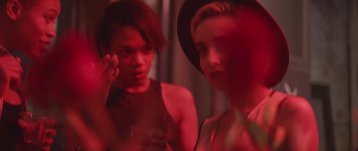 A group of young women are talking in a red lit room
