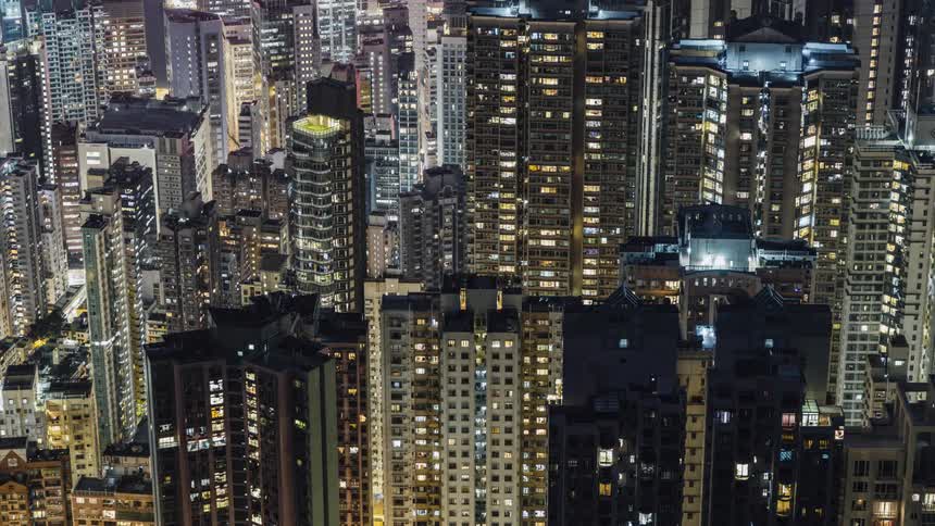 The lights in the windows of skyscrapers turn on and off as the sun sets in a metropolis