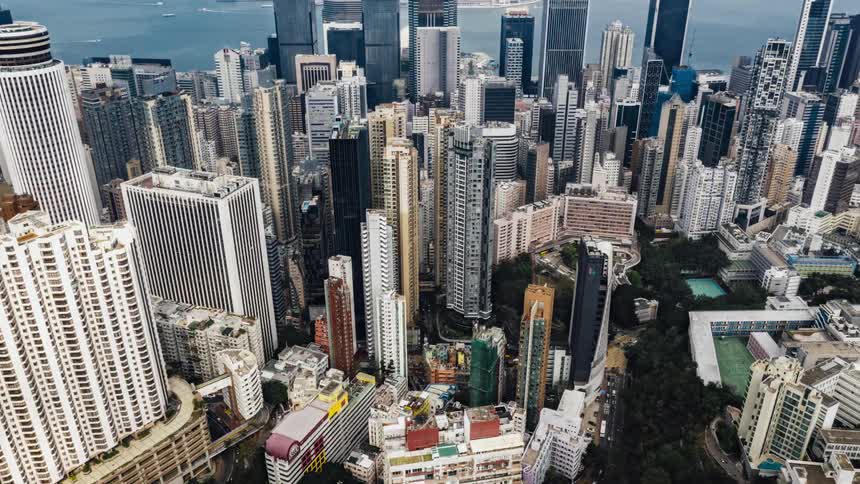 Hong kong citys buildings and skyscrapers with boats traveling in victoria harbor and cars on busy streets