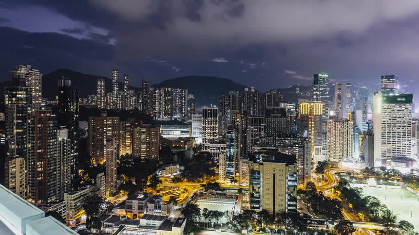 Time lapse of vehicle driving on highway among illuminated buildings at night