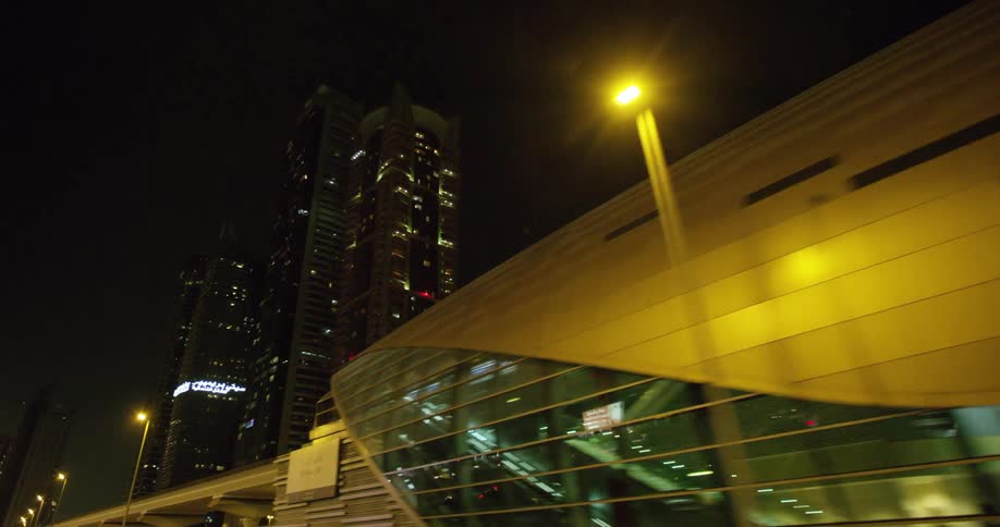 Traveling past the dubai metro station with walkways and beautiful architecture at night