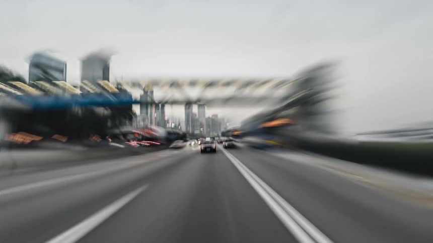 A taxi travels on busy streets around a metropolitan city with skyscrapers and towers all around