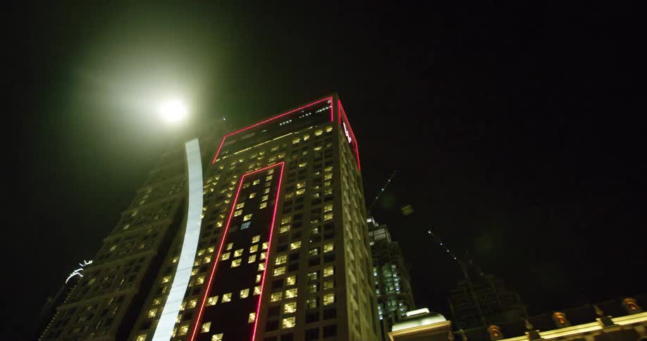 The lights on tall city buildings glow at night in the downtown sky