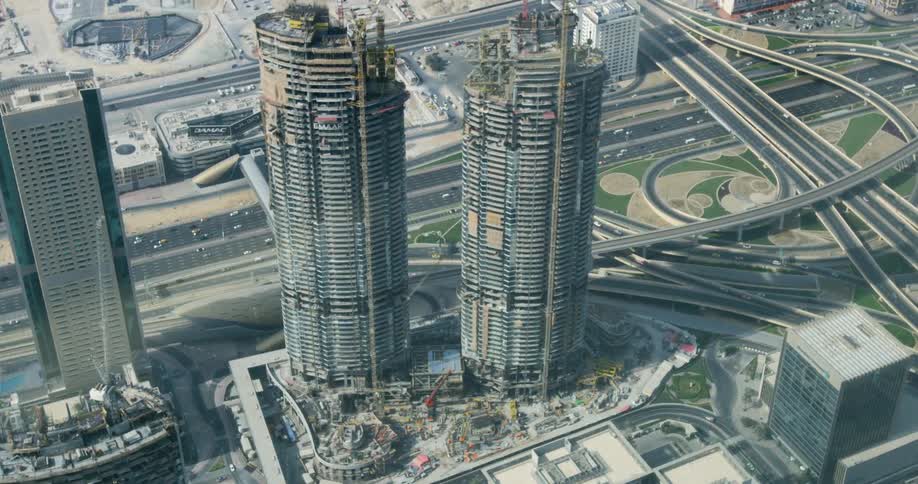 Twin skyscrapers are construction near a freeway downtown
