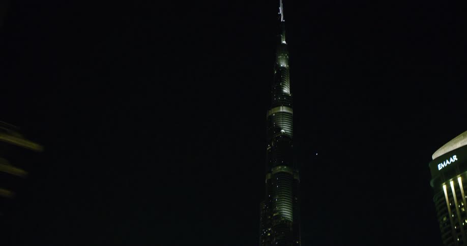 Illuminated city skyscraper seen from moving car in the city at night