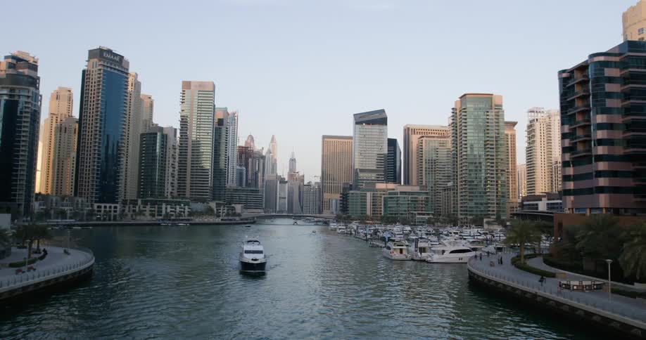 Boat travels across river next to city skyscrapers