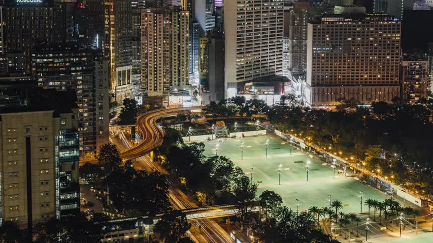 Time lapse of vehicle driving on highway among illuminated buildings at night