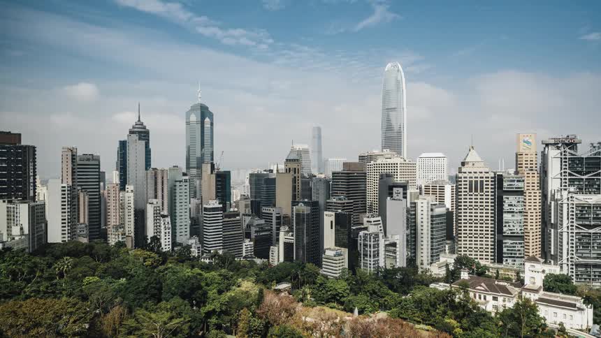 Clouds move across the sky and their shadows move across tall buildings and skyscrapers on the city skyline