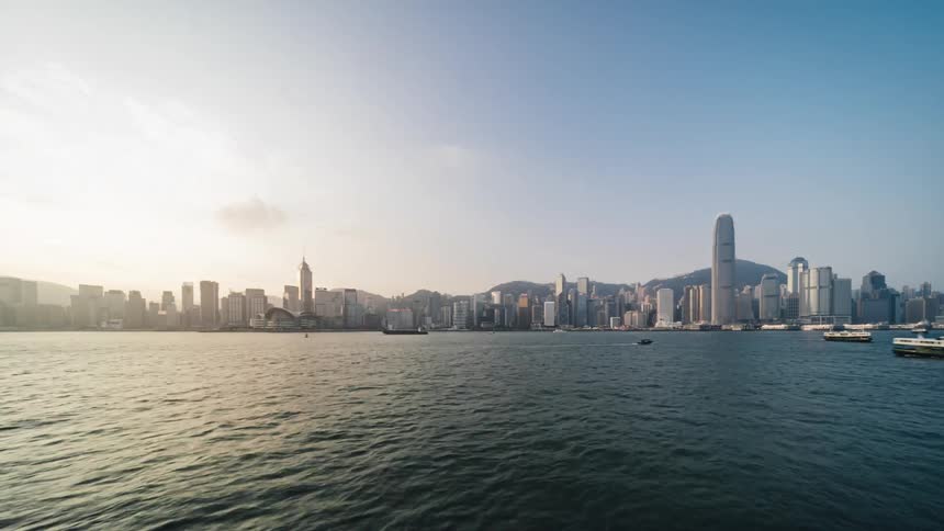 Boats and ships travel on sea with city skyline in the background