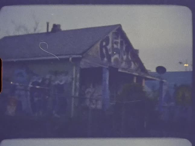 An old house with painted graffiti all over it is in a run down neighborhood