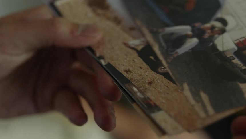 A person looks through a stack of camping photos while indoors