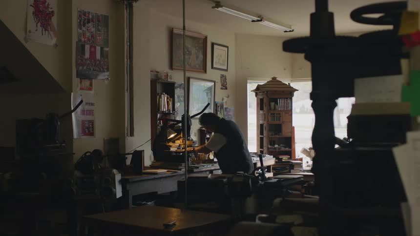 A man in a store presses down on an arm on a printing machine