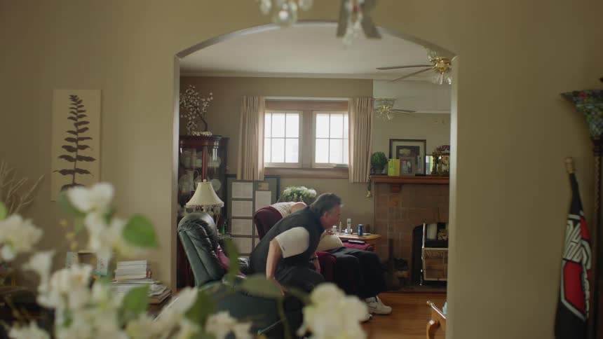 A man walks in the living room to sit down