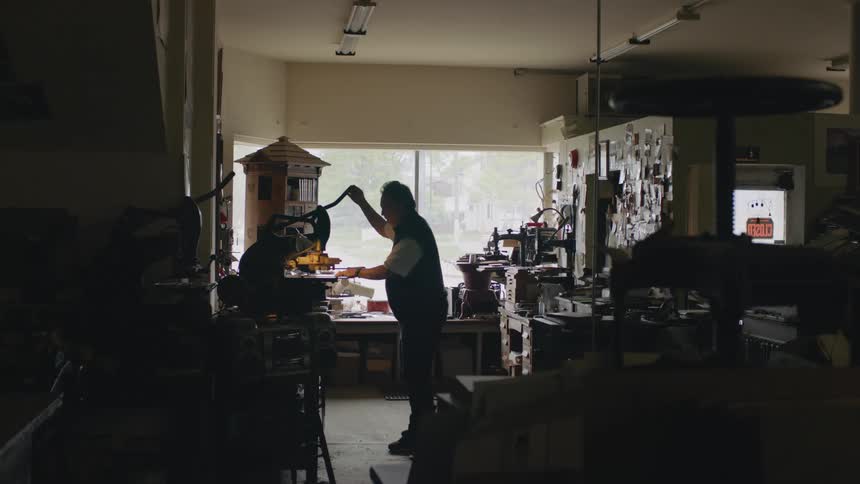 A man is standing in a shop using a press on a page