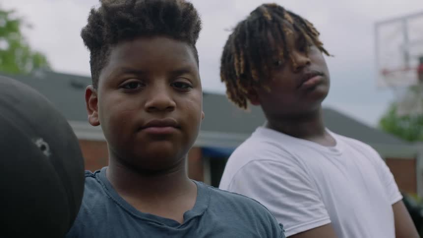 Two teenagers stand outside with a basketball