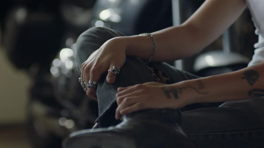 A man sits indoors with his legs crossed