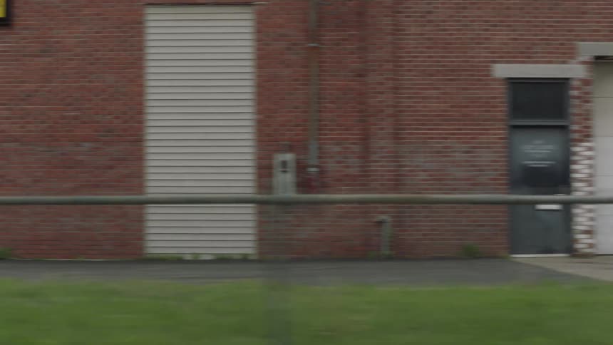 A vehicle drives through a neighborhood passing homes and a small church