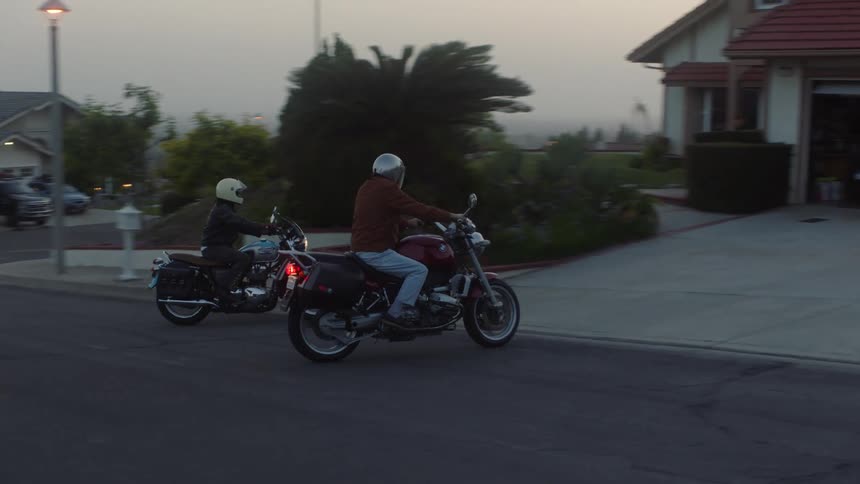 Men on motorcycles arrive at a house and drive into the garage