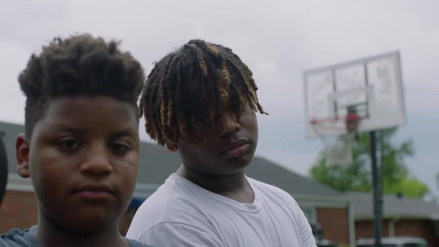 Two teenagers are standing by a basketball hoop