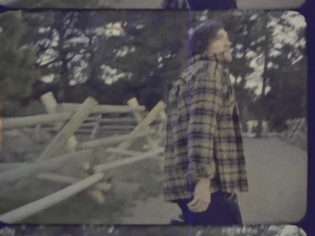 A man walks down a fenced in sidewalk