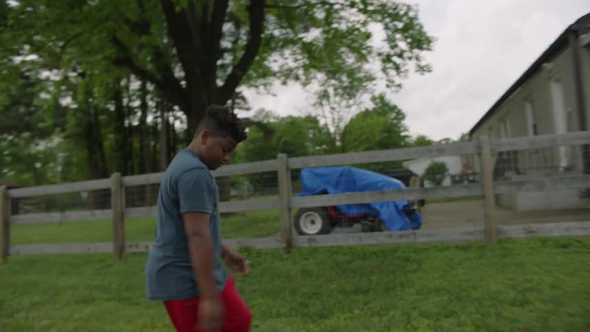 Youths pass football back and forth in yard near home