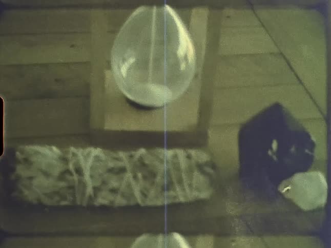An hourglass is on a table and there are crystal stones next to it