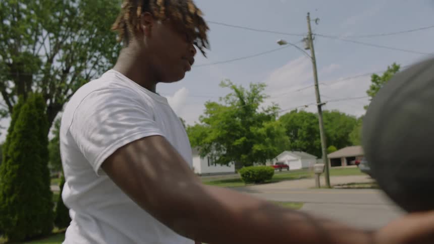 A teenager gets the basketball after it goes through the hoop and tosses it to a friend