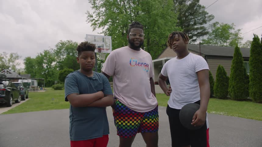 Father and sons pose with basketball at home near basketball hoop