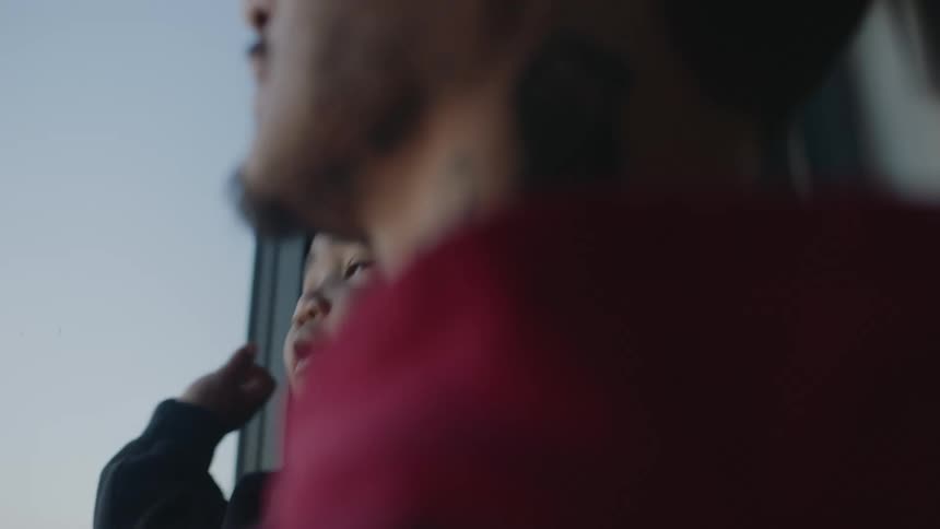 A father is holding his baby on a porch as they talk and smile