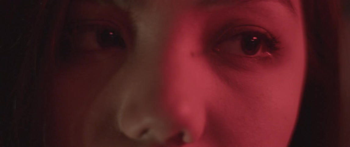 A woman blinks in a dim room