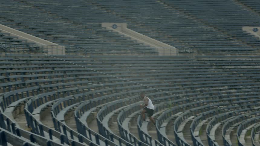 A man sprints up bleachers in a stadium