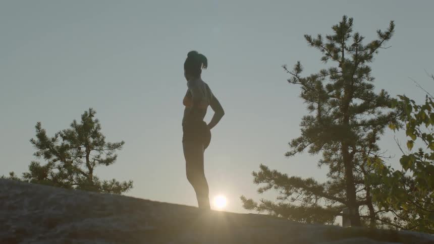 A woman stands and pants in the woods