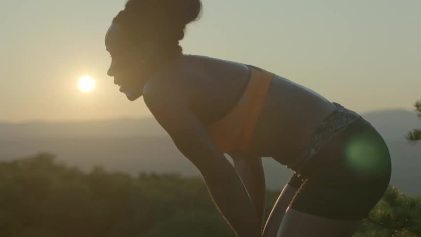 A woman rests after running at dusk