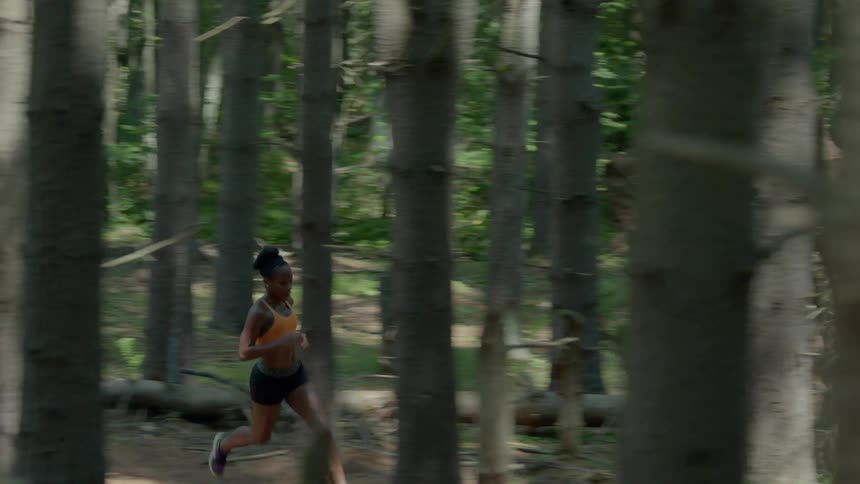 A woman running through a thick forest