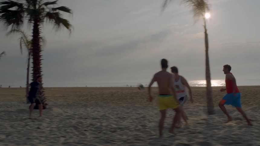 Boys play soccer on a beach
