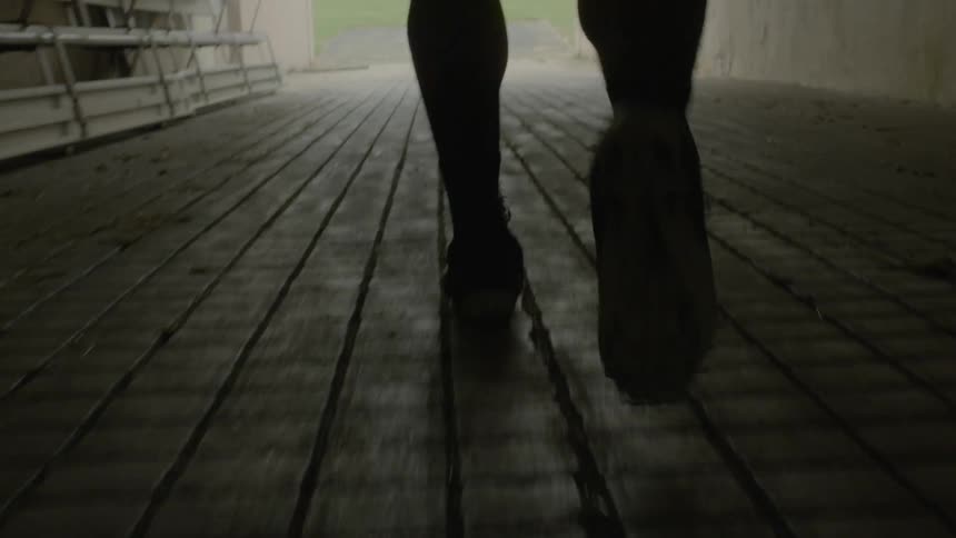 Man walking in a dark area towards an exit
