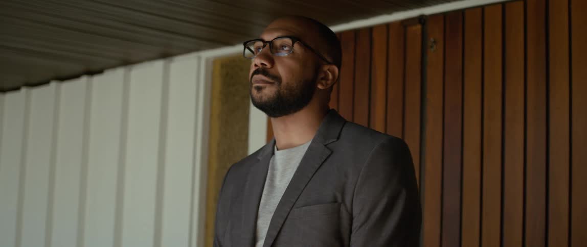 A man is standing in a room and nodding his head as he looks around