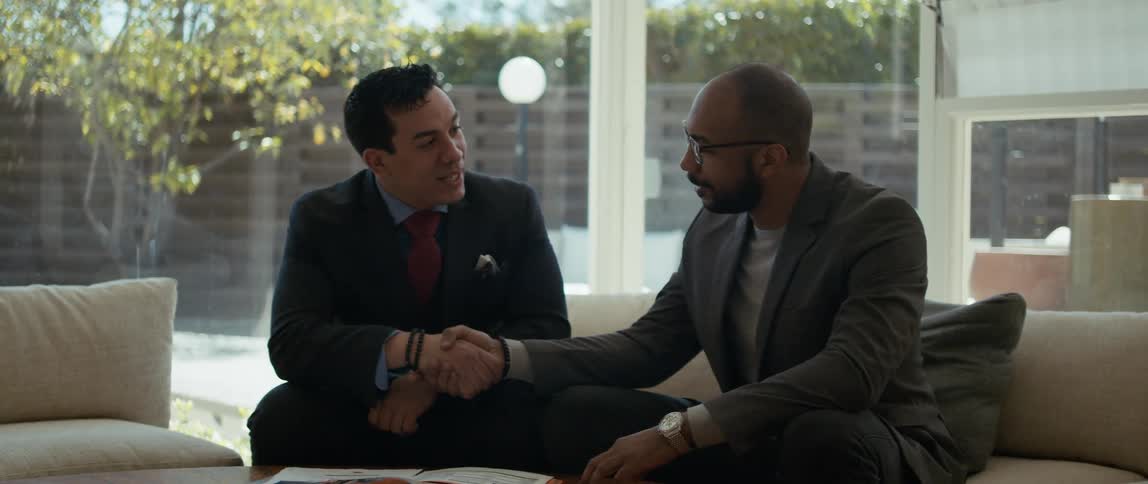 Two business men shake hands while holding a discussion