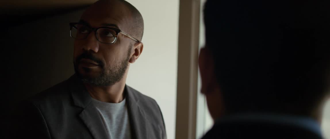 A man is standing in a room and nodding his head as he looks around