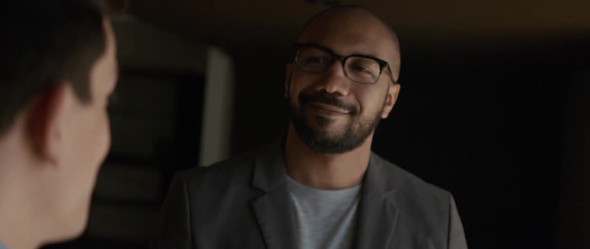 Two men are talking and one man smiles and nods his head as he listens to the other man speak